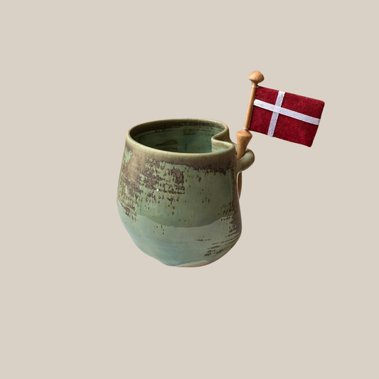 Grøn keramik kop med tilhørende flag.