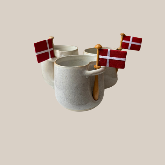 Lys beige keramik kop med tilhørende flag.