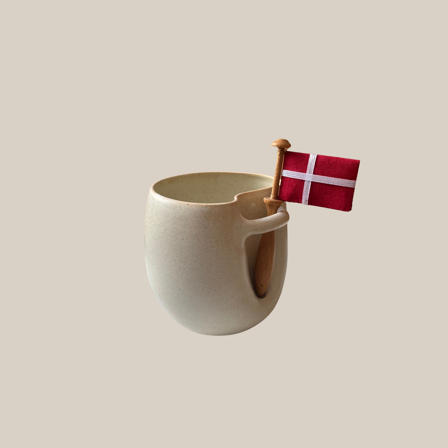 Flødefarvet keramik kop med tilhørende flag.
