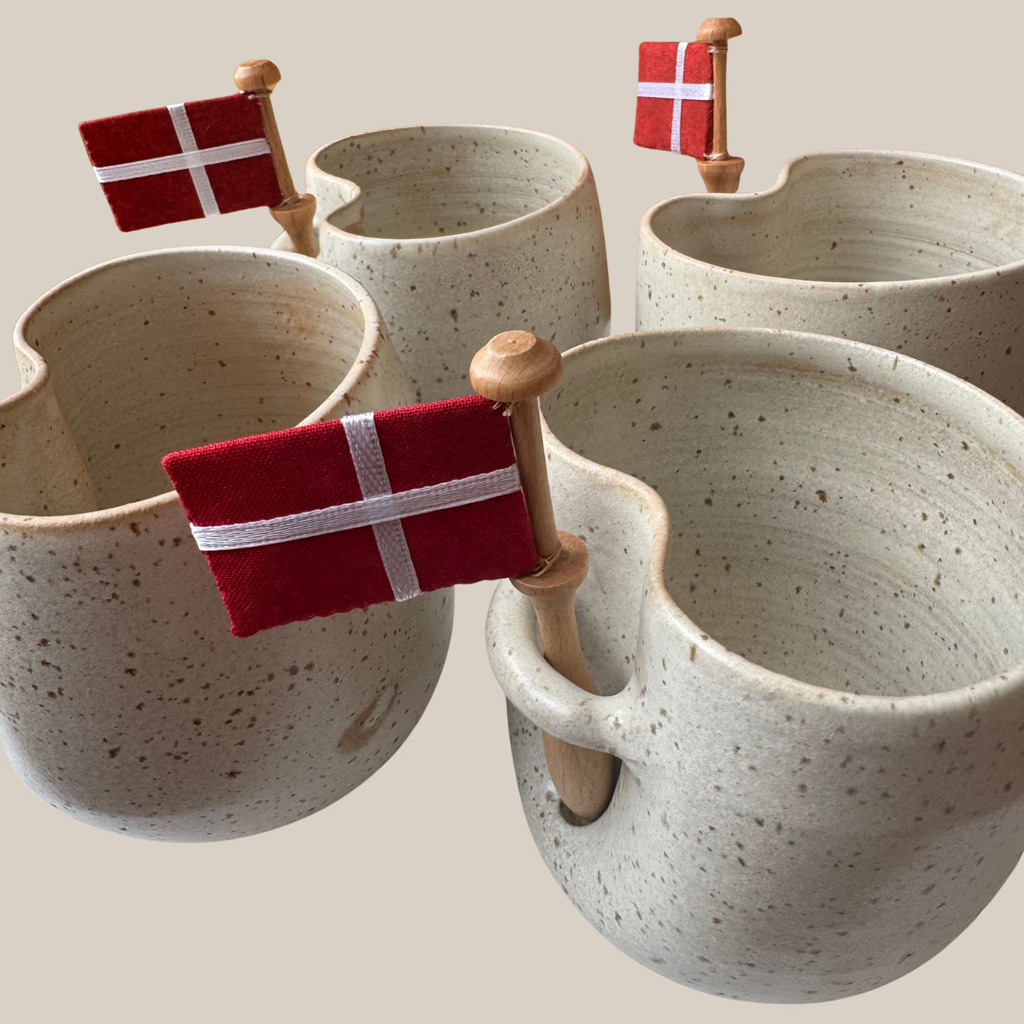 Lys beige prikket keramik kop med tilhørende flag.