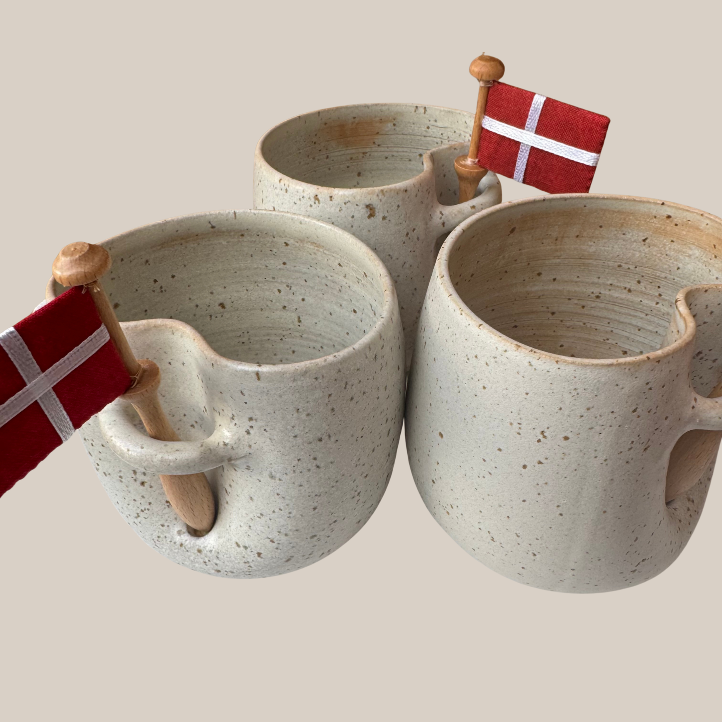 Lys beige prikket keramik kop med tilhørende flag.