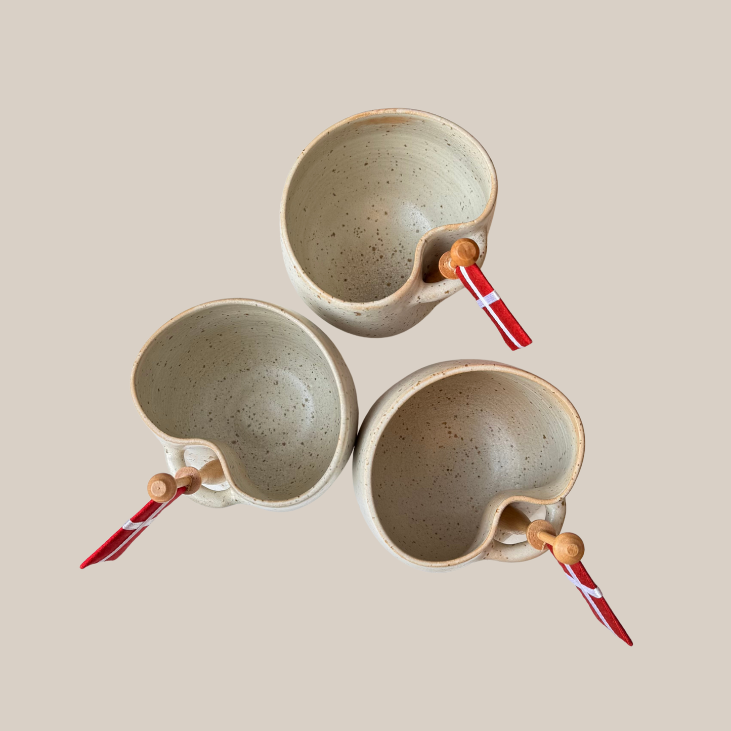 Lys beige prikket keramik kop med tilhørende flag.