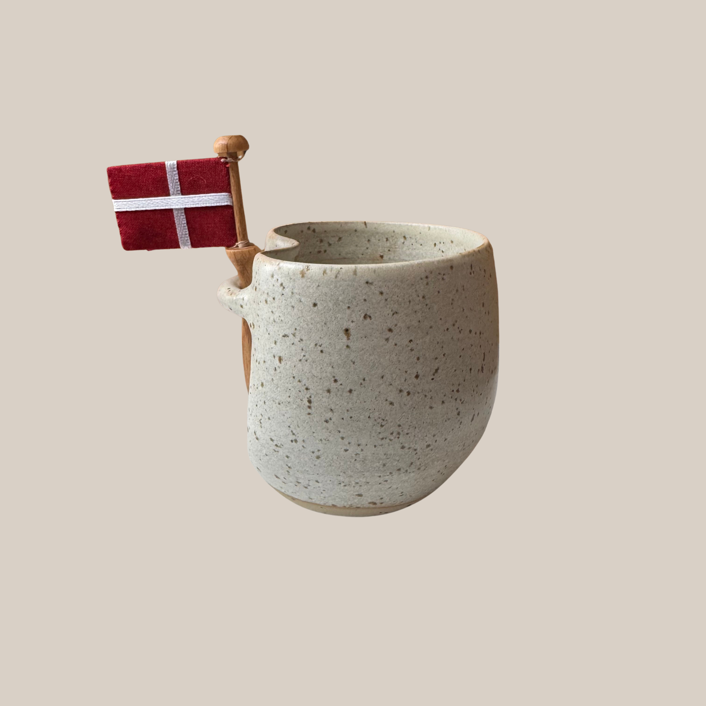 Lys beige prikket keramik kop med tilhørende flag.