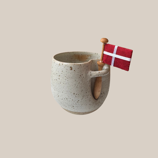 Lys beige prikket keramik kop med tilhørende flag.