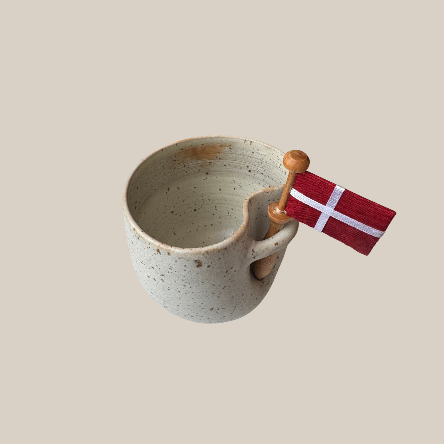 Lys beige prikket keramik kop med tilhørende flag.