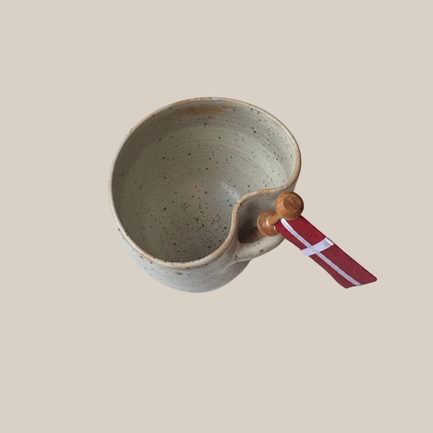 Lys beige prikket keramik kop med tilhørende flag.