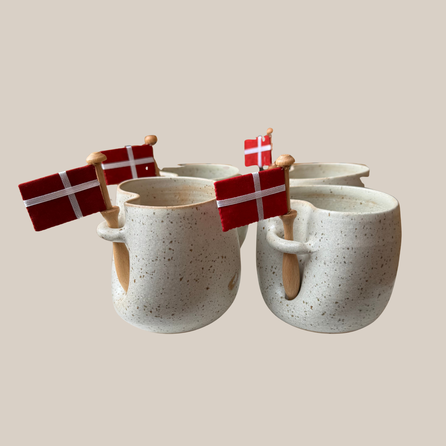 Lys beige prikket keramik kop med tilhørende flag.