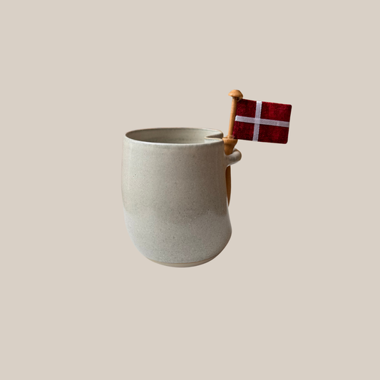 Lys beige keramik kop med tilhørende flag.