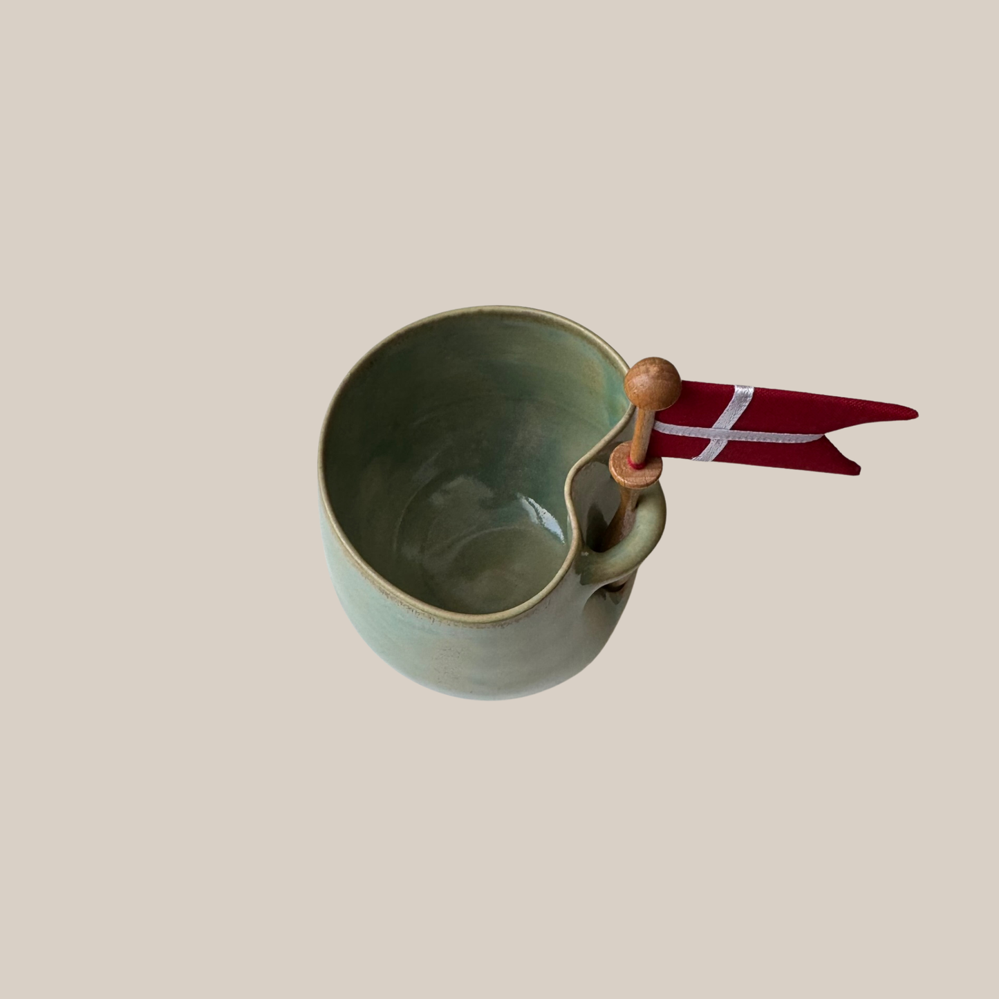 Grøn keramik kop med tilhørende flag.