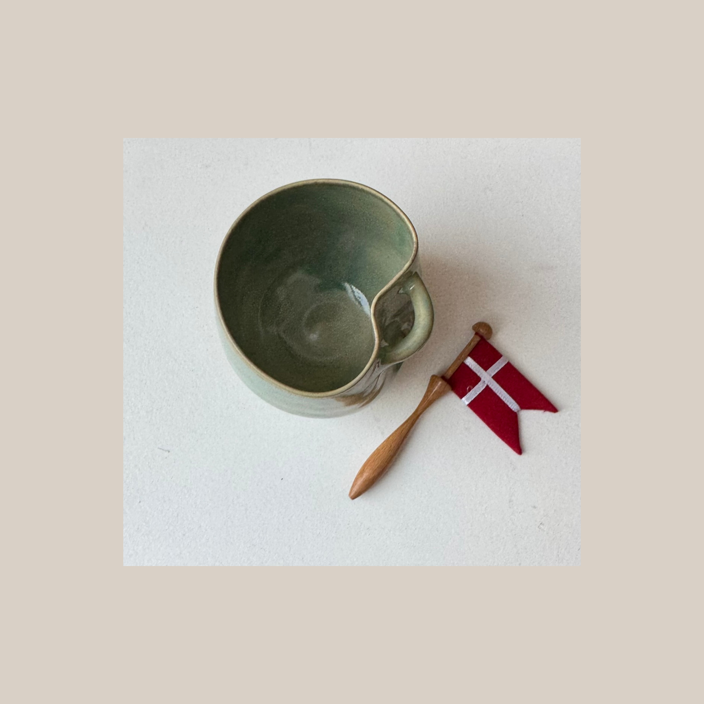 Grøn keramik kop med tilhørende flag.