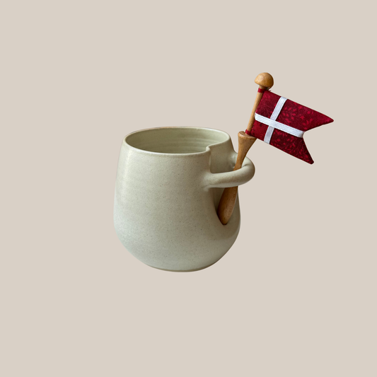 Lys beige keramik kop med tilhørende flag.
